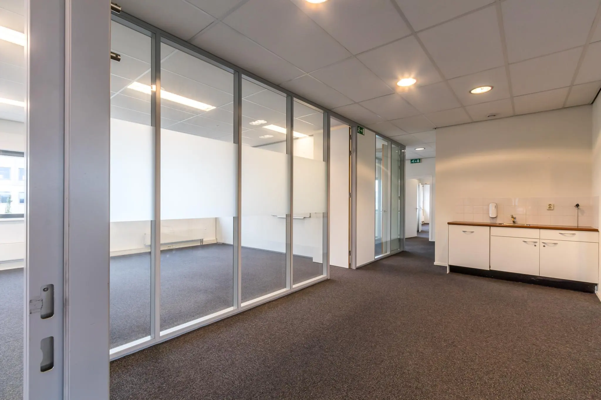 Kantoorruimte aan de Lage Biezenweg met glazen scheidingswanden en een kitchenette.